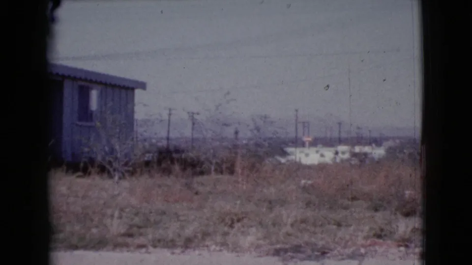 1964 Cottonwood, Arizona view of a modest house and dry overgrown yard, partly bordered by a dark foreground frame.