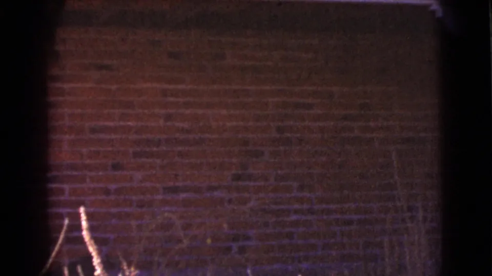 1964 Cottonwood, Arizona frame dominated by a red brick exterior wall, dry foreground plants, and small-gauge film edge artifacts.