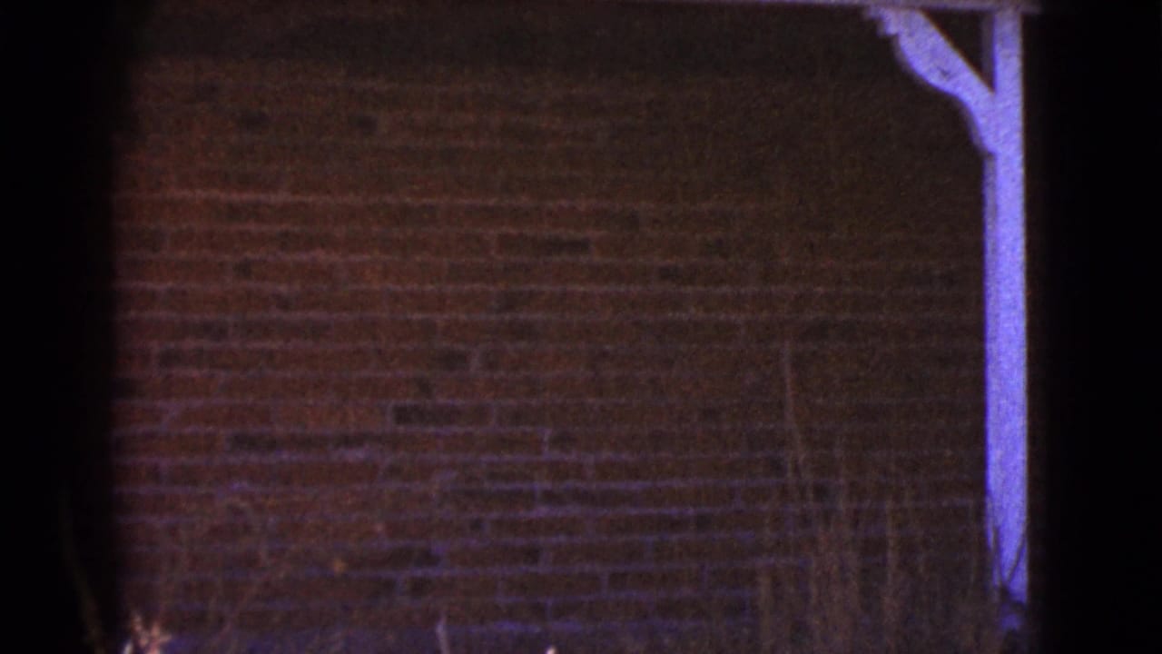 Dark brick wall with a white-painted porch support under a roof eave.
