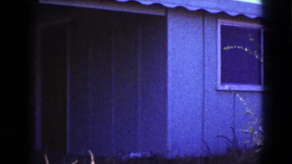 1964 Cottonwood, Arizona frame of the pan revealing more siding and a small dark window on the house exterior.