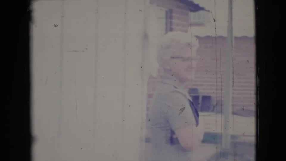 The woman turns and smiles near an exterior wall in Cottonwood, Arizona, with brick and window details in the background.