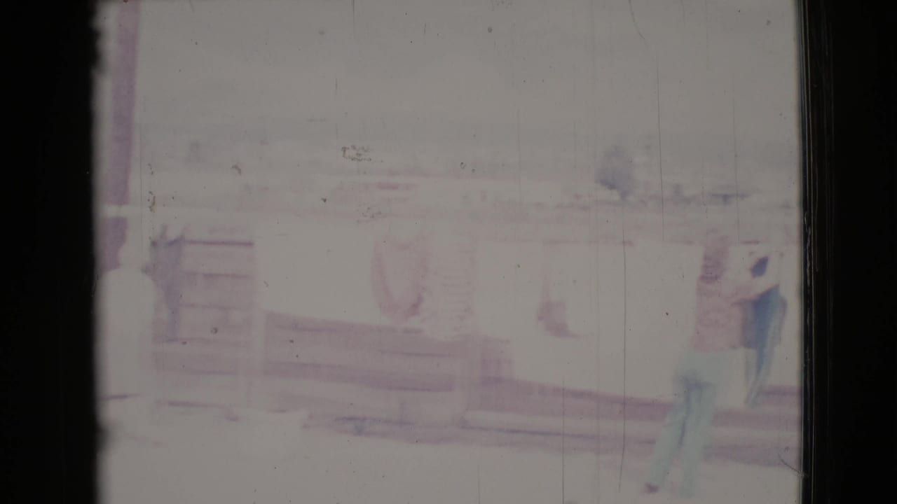 Two women stand near a clothesline on a bright porch-like outdoor area.