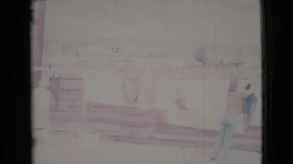 In 1964 Cottonwood home-movie footage, two women appear beside laundry on a line in a washed-out outdoor porch scene.