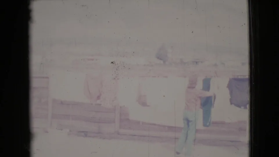 The Cottonwood, Arizona frame shows a woman in green pants near laundry on a line, with another woman faintly visible in the bright scene.