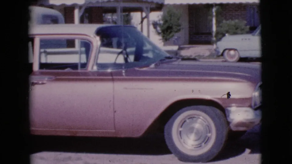 A side view shows a mid-century two-tone sedan with a pale blue car behind it on a Cottonwood, Arizona neighborhood street.
