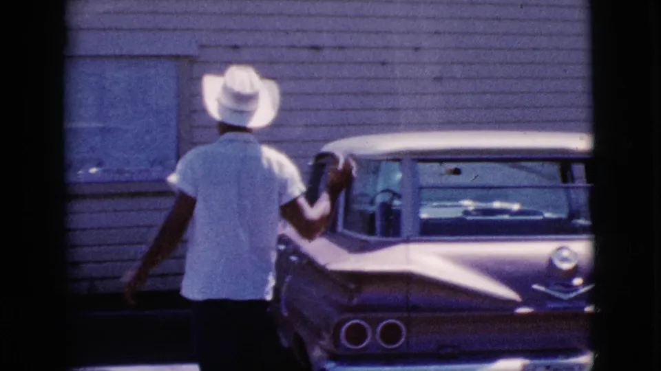 The man approaches the parked sedan in Cottonwood, Arizona, with his arm raised near the passenger-side door or window.