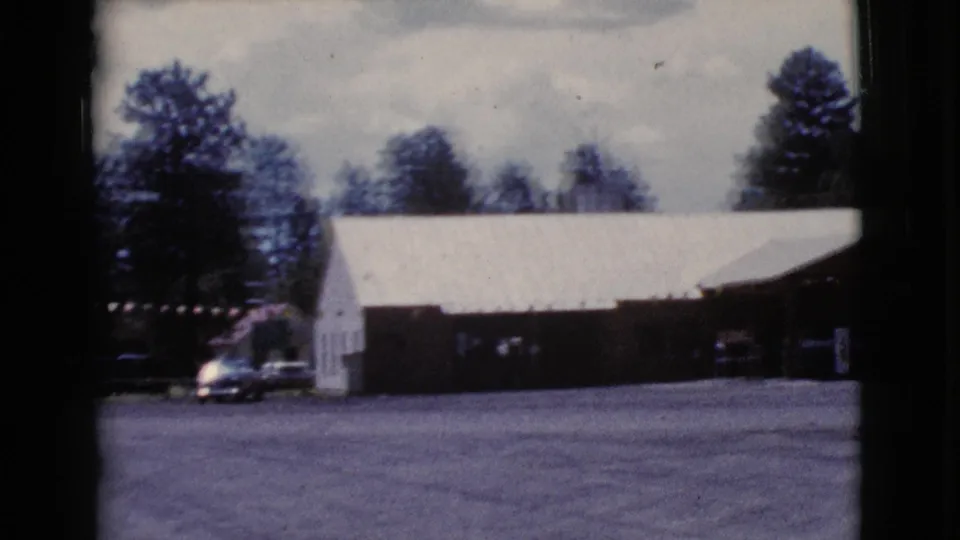 The final frame shows the side of the Cottonwood roadside building, a parked car near the wall, open pavement, and trees under a bright sky.