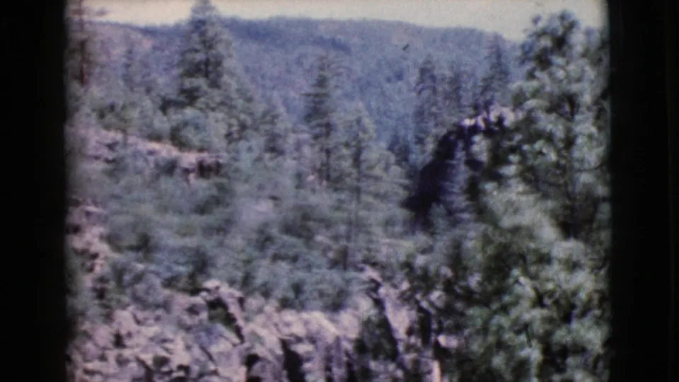 1964 Cottonwood, Arizona 8mm view looking across a soft-focus forested canyon and rocky hillside.
