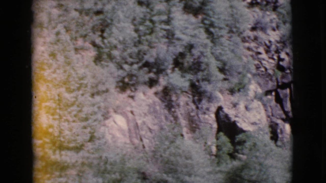 Dark-bordered 8mm frame showing a mottled rocky cliff surface in soft faded color.