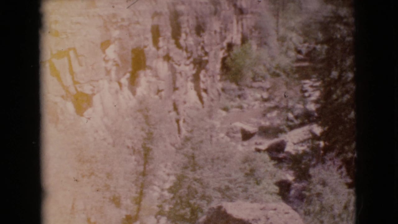 Pale rocky cliff texture with dark vertical frame edges and faded warm tones.