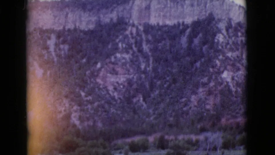 A purple-shifted 8mm frame of a wooded Arizona ridge near Cottonwood, with visible grain, soft detail, and dark frame edges.