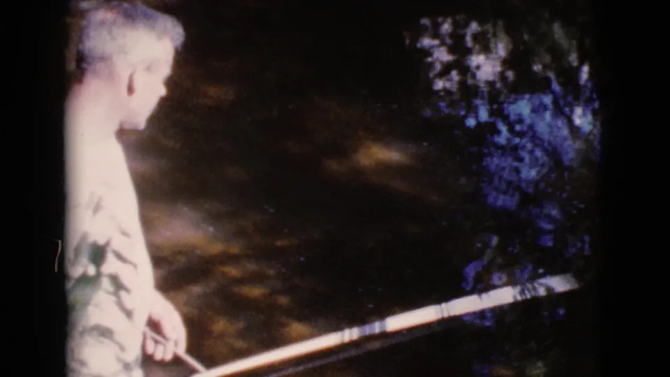 In Cottonwood, Arizona, 1964, a male figure stands near a murky stream with a fishing rod in soft 8mm home-movie footage.