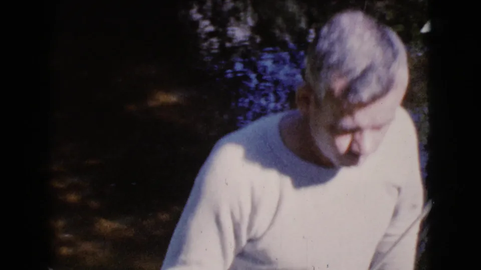 A closer 8mm frame shows the male figure leaning forward near the Cottonwood stream, with dark water and foliage behind him.