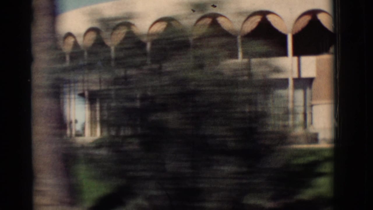Blurred roadside view of the same arched building behind trees.