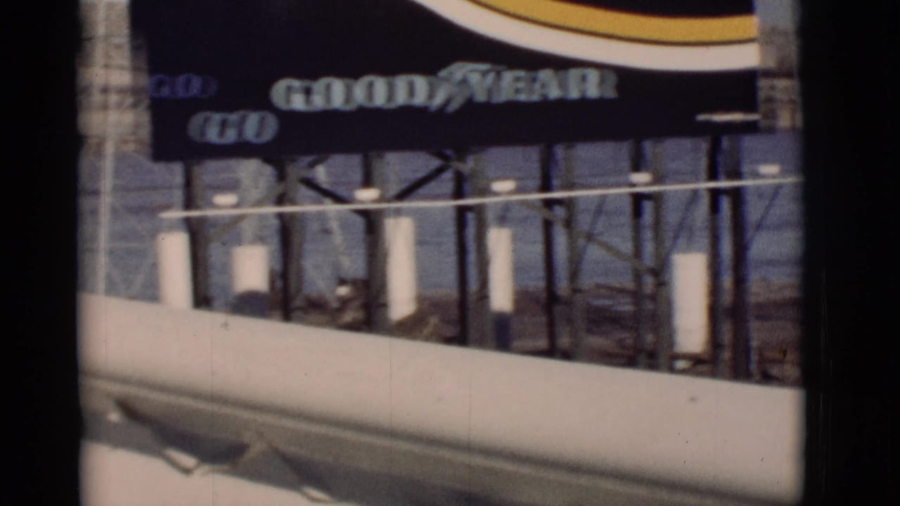 Goodyear billboard over white posts, railing, and river water in the background.