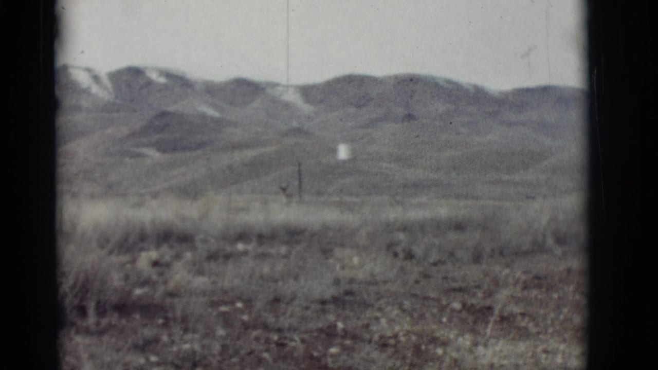 Open plain and distant mountains framed by dark 8mm film edges.
