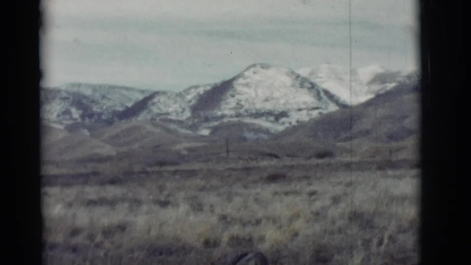 New Mexico mountain ridges and open grassland appear in a faded 1960s 8mm home-movie frame.