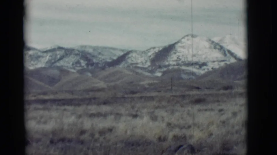 Faded 8mm frame of a New Mexico ridge line, rolling foothills, and dry desert grassland.