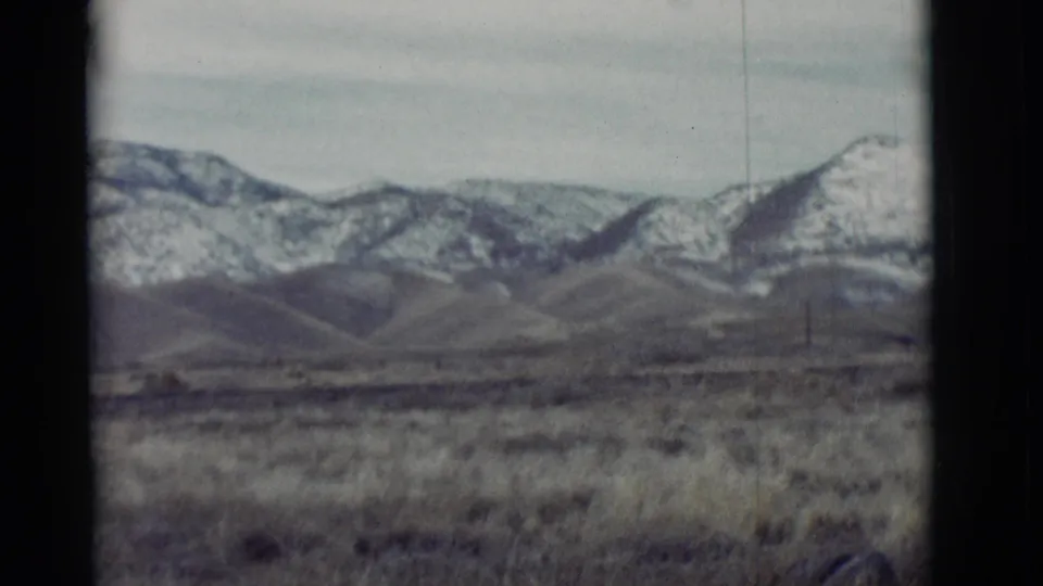 1964 New Mexico home-movie view of scrubby grassland below a distant snow-lined mountain range.