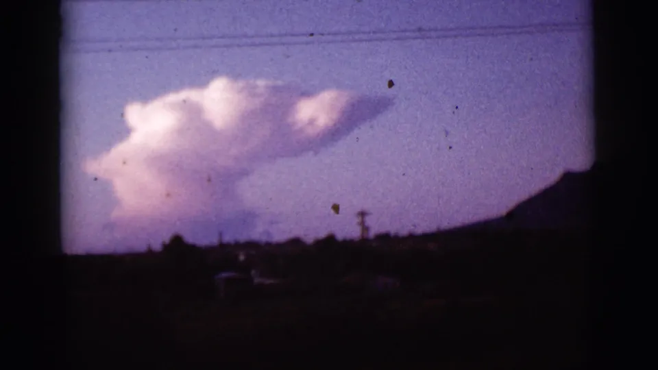 1965 Tucson-area 8mm frame showing an unusually shaped cloud over a silhouetted hillside and utility lines.