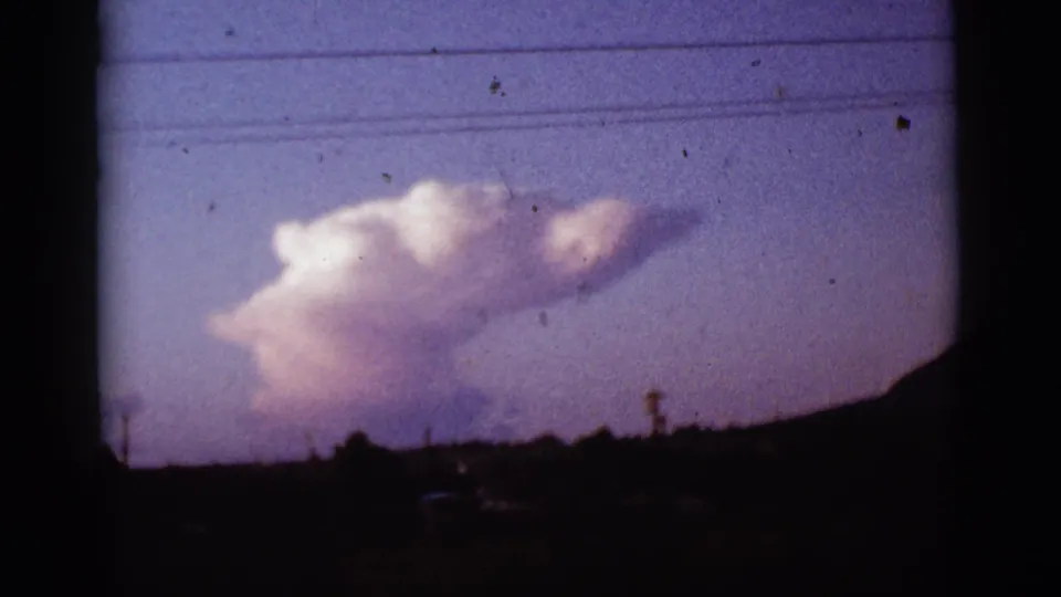 1965 Tucson-area 8mm frame showing the cloud formation over a silhouetted landscape and visible film borders.