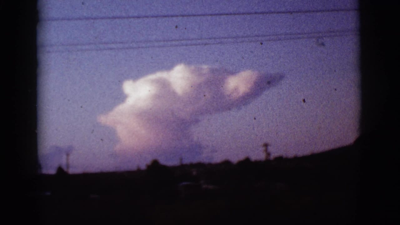 Large smoke plume above a dark horizon with utility lines across a blue-purple sky.
