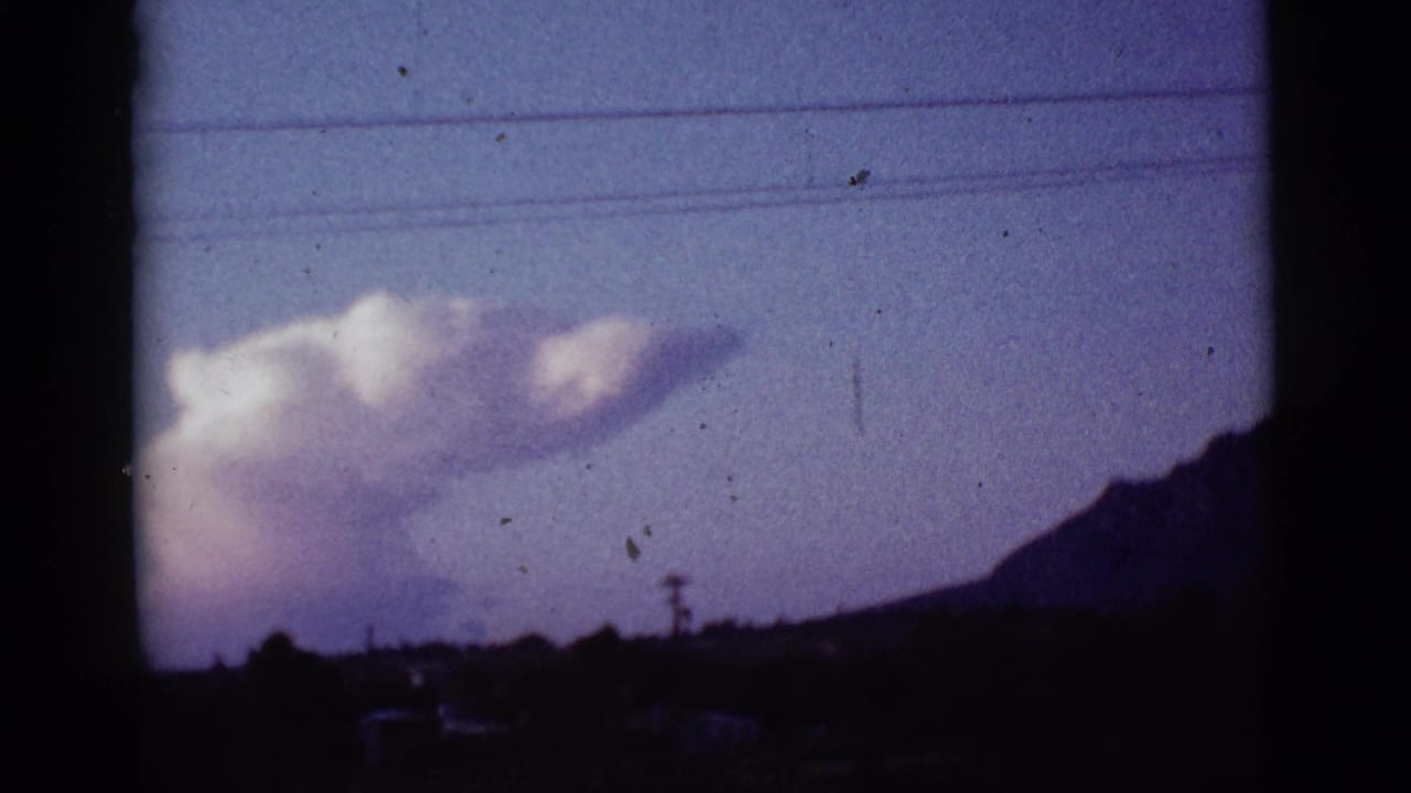Large cloud over a dark hill with utility lines crossing the purple sky.