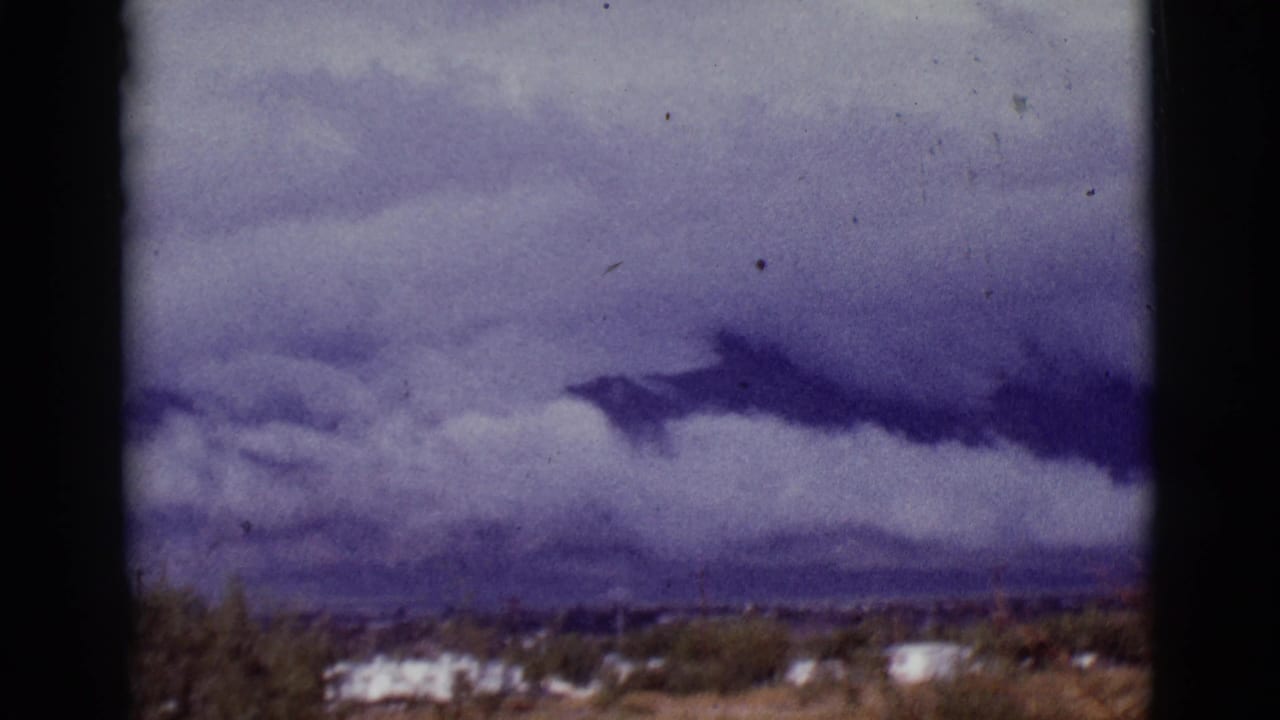 Dark cloud band over a desert horizon with trailers and mountains in the distance.