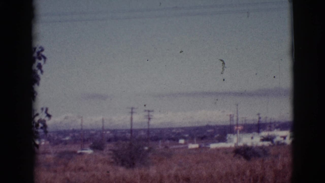 Open desert town edge with utility poles and low buildings beneath clouds.