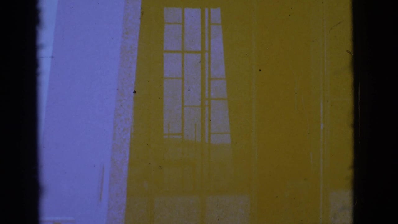 Pale building facade with tall window shapes and strong purple-yellow film color shift.