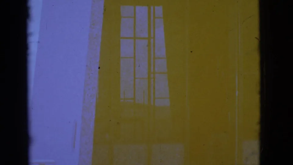 1966 Clarkdale 8mm frame showing a pale structure with tall windows, dark gate edges, grain, and purple-yellow dye shift.