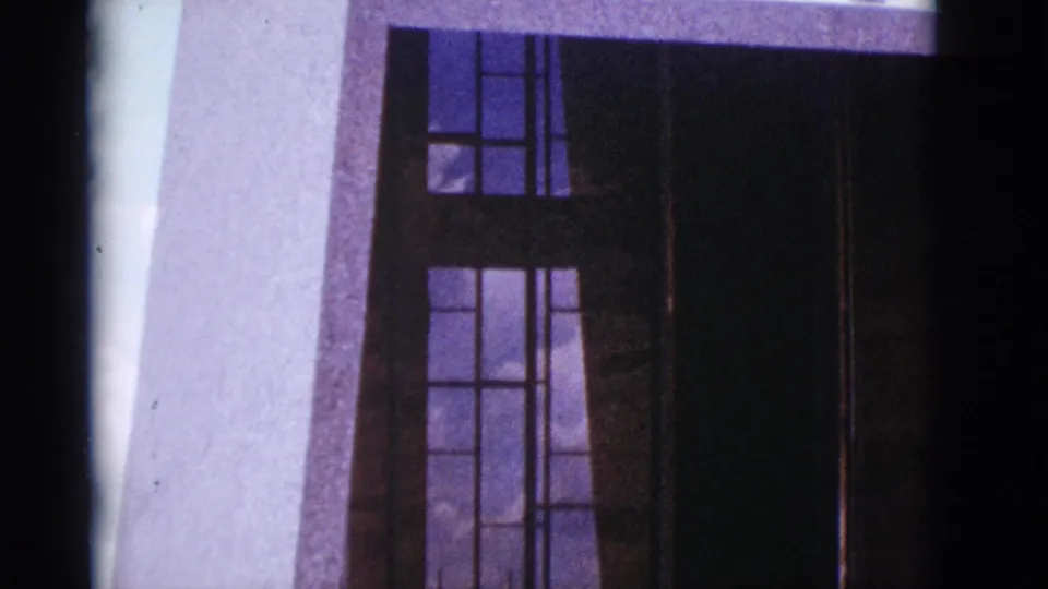 1966 Clarkdale, Arizona frame with dark-framed glass windows, a pale facade strip, vertical lines, and purple-blue 8mm color shift.
