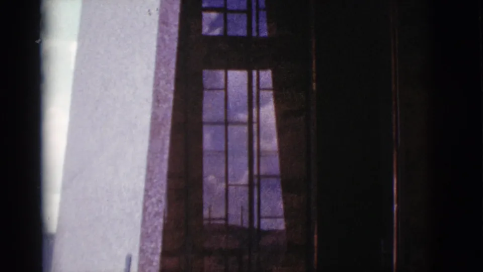 1966 Clarkdale, Arizona 8mm frame showing tall multi-pane windows set into a textured stone exterior.