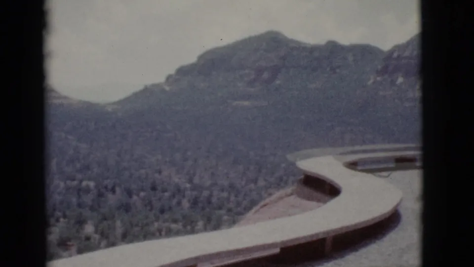 1966 8mm view near Clarkdale, Arizona, with a curved concrete overlook edge framing scrub desert and distant rocky hills.
