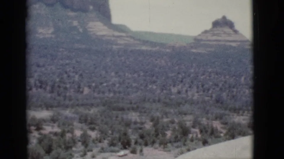 1966 8mm view near Clarkdale, Arizona, looking across scrubland toward layered buttes and hazy desert mountains.