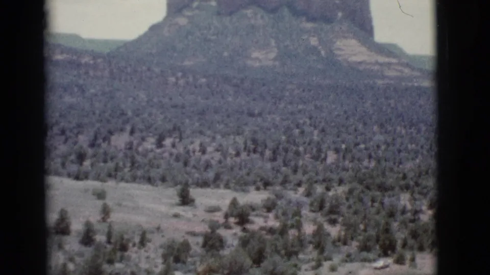 1966 8mm frame near Clarkdale, Arizona, with an open scrub valley below rocky slopes and distant layered formations.