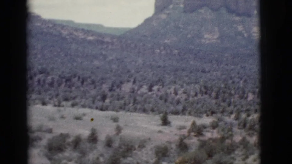 1966 Clarkdale, Arizona 8mm frame showing a broad scrub valley with scattered trees and distant layered mountains.