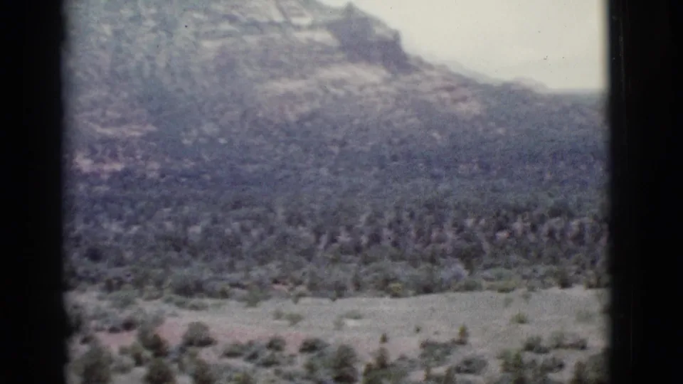 1966 Clarkdale, Arizona frame with a tree-dotted valley and distant mountain softened by faded 8mm color.