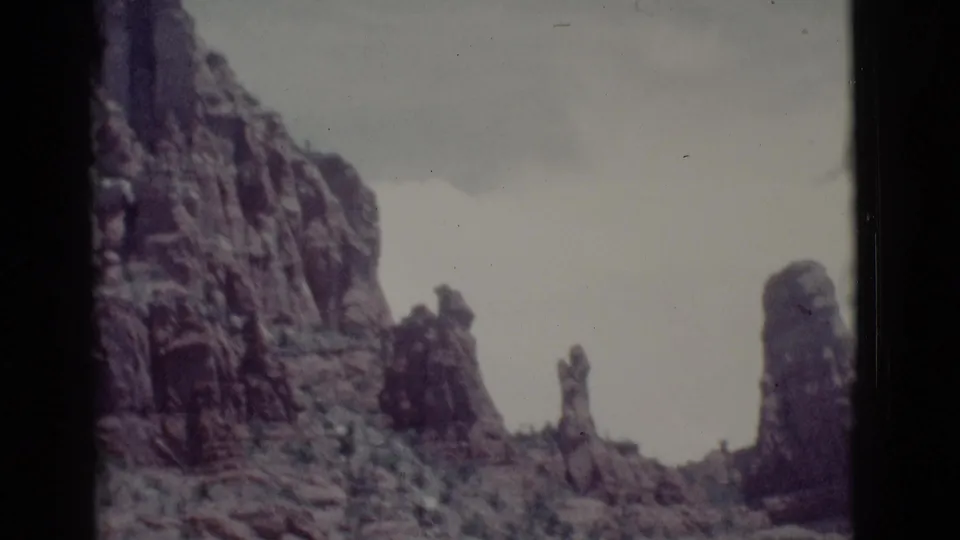 1966 Clarkdale, Arizona 8mm frame showing multiple upright red rock formations, scrub vegetation, and hazy sky.