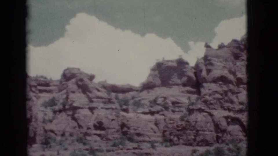 Clarkdale-area desert rocks sit below large white clouds in a soft, faded 1960s 8mm frame.