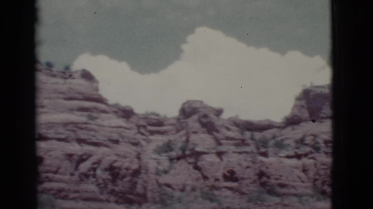 1966 8mm view of layered red rock hills near Clarkdale, Arizona, with pale clouds above and no people visible.