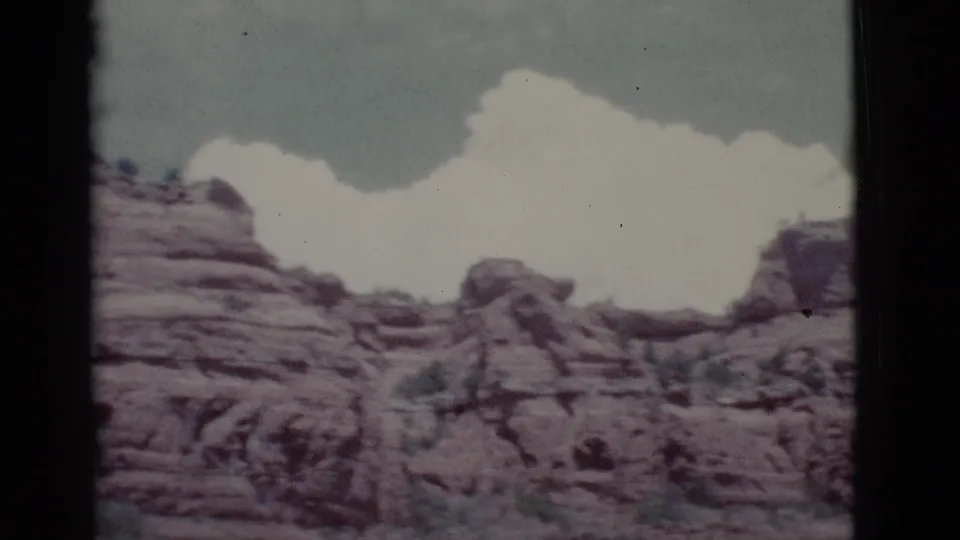 1966 8mm view of layered red rock hills near Clarkdale, Arizona, with pale clouds above and no people visible.