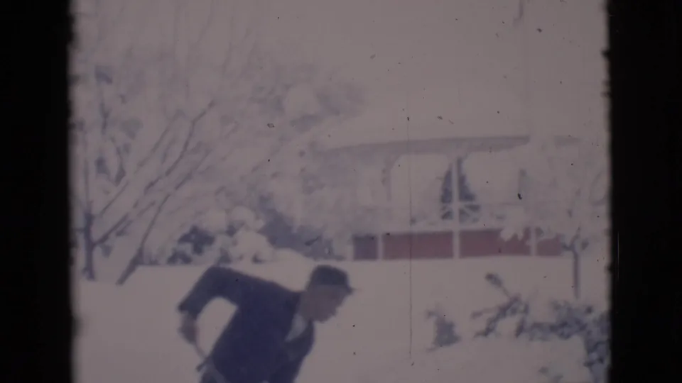 In 1966 Clarkdale, Arizona, a man in a dark coat and hat appears to shovel deep snow in a residential yard.