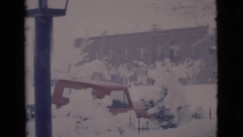 Clarkdale, Arizona 1966 home-movie frame showing deep snow, a red car, bare trees, and a brick residential building.