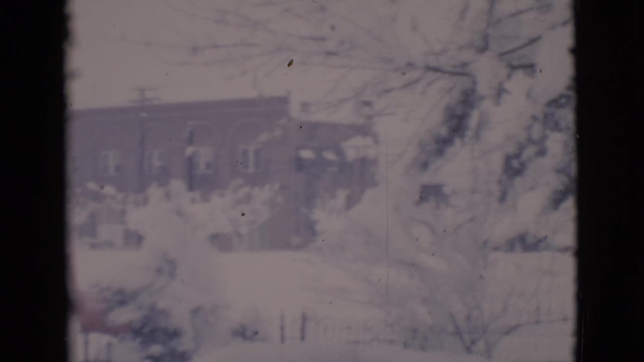 Snowy residential view seen through dark vertical frame edges.