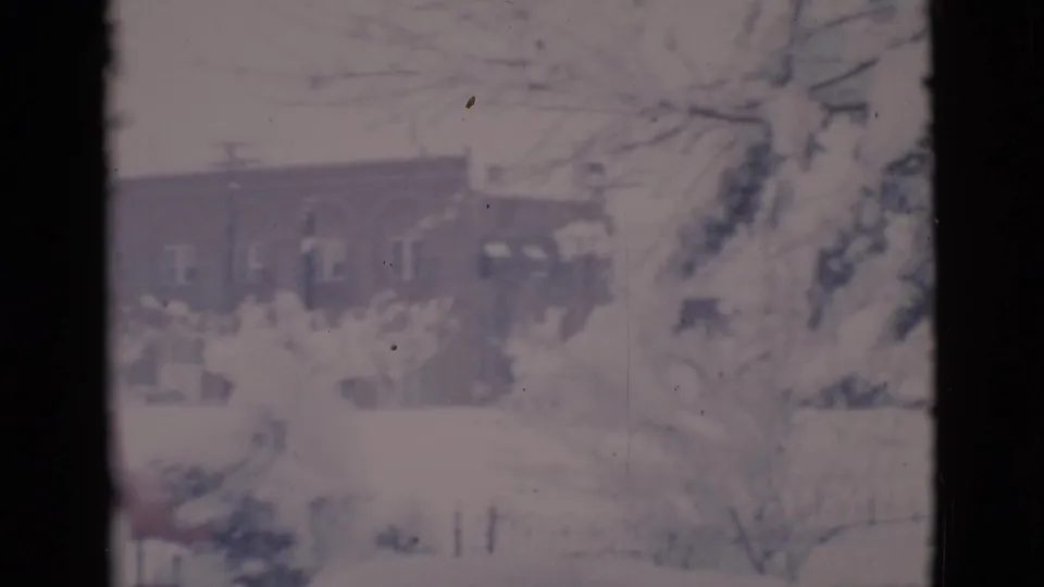 A 1966 Clarkdale winter view shows snow-covered trees and a brick building through dark film or window edges.