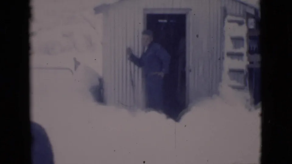 A man appears at a shed doorway in a deep snowy Clarkdale residential scene from 1966 home-movie footage.