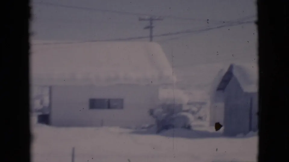 1966 Clarkdale, Arizona frame showing a snow-covered house and small shed beneath overhead utility wires.