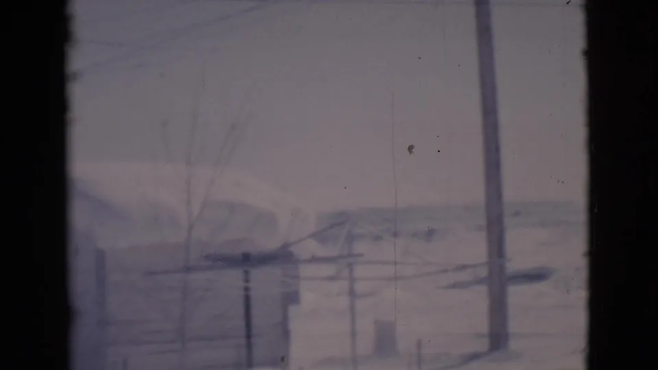 1966 Clarkdale, Arizona frame with snow-covered terrain, utility poles, bare trees, and low sheds partially obscured by dark frame bars.