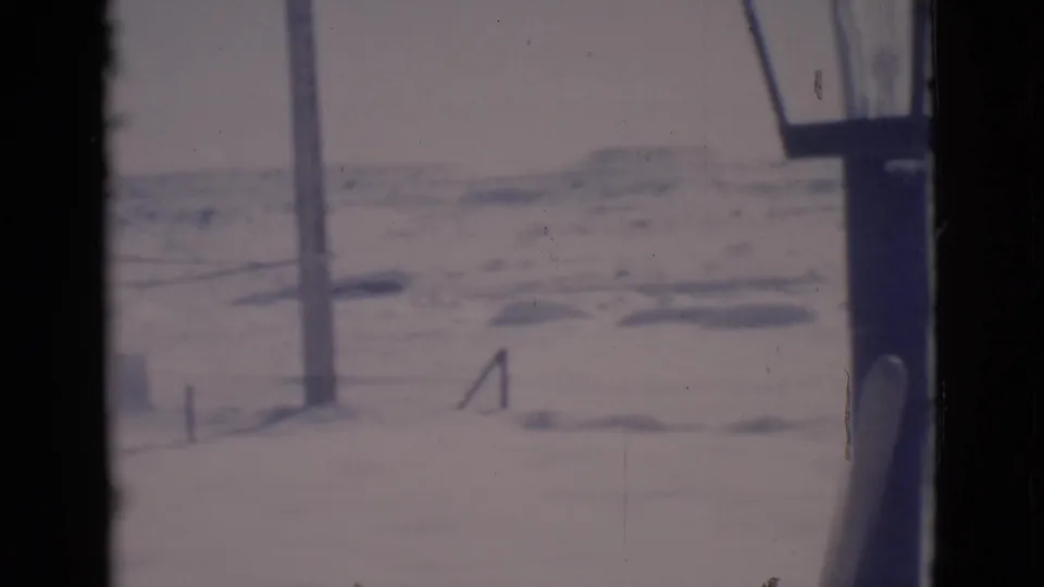 1966 Clarkdale, Arizona frame showing a utility pole, snow-covered ground, faint rails or fence lines, and dark interior framing.
